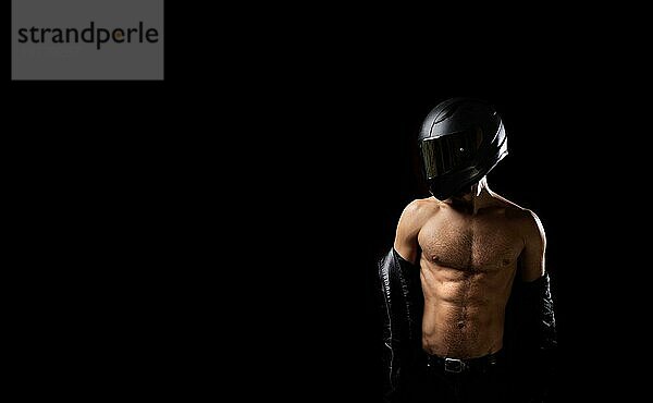 Sportlicher männlicher Motorradfahrer mit nacktem  muskulösem Körper und Helm auf schwarzem Hintergrund. Sicherheitskonzept für Motorradfahrer