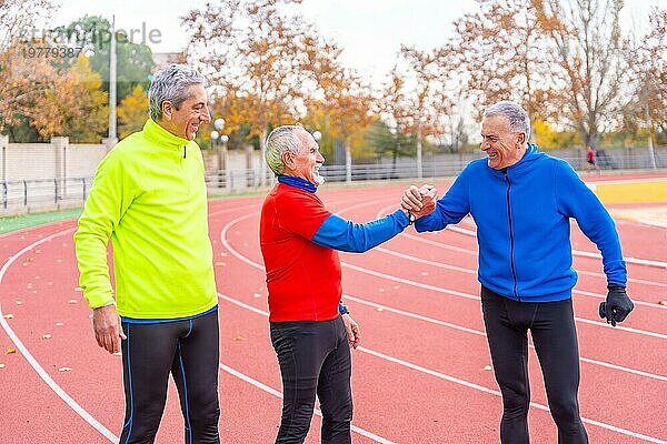 Glückliche ältere Freunde gratulieren zu einem schönen Lauftraining auf einer Outdoor Bahn