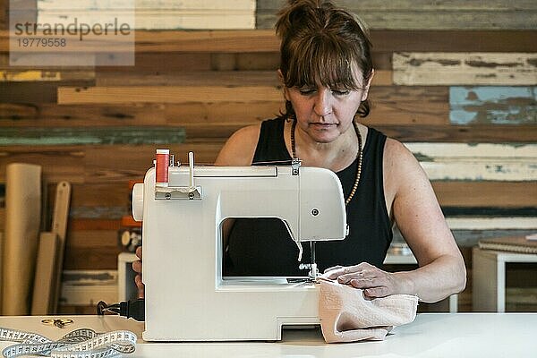 Modedesignerin an der Nähmaschine in ihrem Atelier