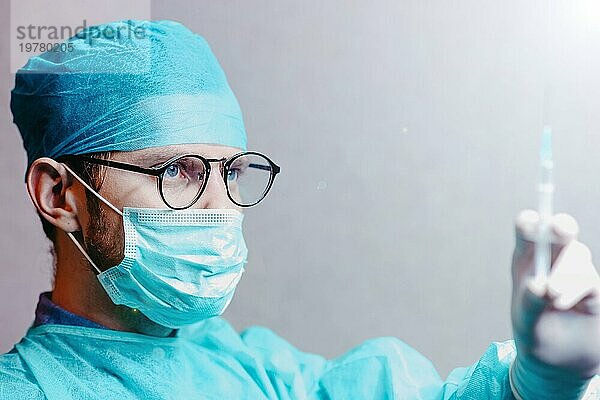 Junge männliche Chirurg Arzt in Uniform mit einer Spritze ist die Vorbereitung für die Injektion