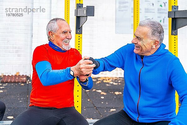 Ältere Männer amüsieren sich gemeinsam auf einem Sportplatz und beglückwünschen sich selbst