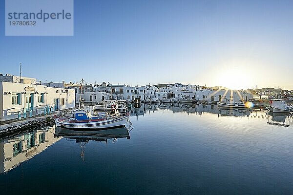 Fischerboote im Hafen von Naoussa bei Sonnenuntergang  spiegeln sich im Meer  Sonnenstern  Weiße kykladische Häuser  Naoussa  Paros  Kykladen  Griechenland  Europa