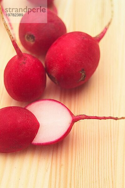 Frischer roter roher Rettich über Kiefernholztisch Großaufnahme