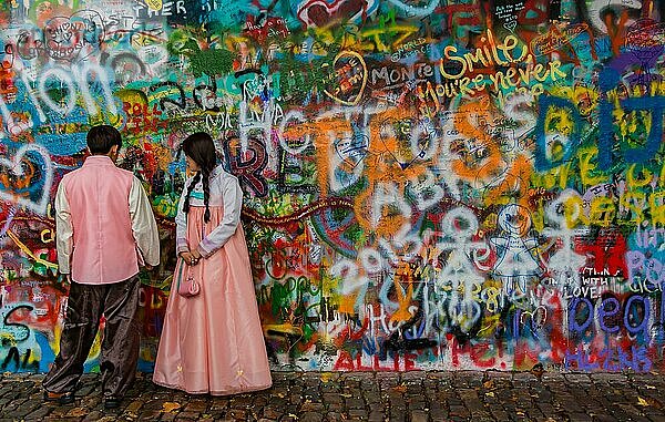 Ein Bild von einem Trachtenpaar  das vor der John Lennon Mauer posiert (Prag)