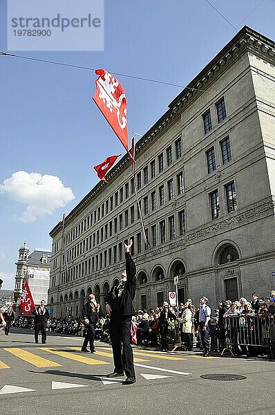 Schweiz: Wehende Schweizer Fahne vor der Schweizerischen Nationalbank in Zürich | Fahnenschwingen vor dem Gebäude der Zürcher Nationalbank am Sechseläuten  dem Fest der Zünfte