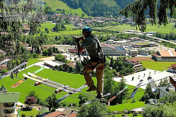 Tirol: Ein Mann balanciert im Zillertaler Hochseilgarten über die Skibretter. Ein Mann balanciert im Zillertaler Hochseilgarten über die Skibretter in Tirol