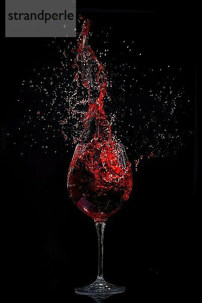 Ein Weinglas mit einem eleganten Rotweinschwall vor einem dunklen Hintergrund  der Bewegung und Dynamik einfängt  Splash  Feier  Geburtstag