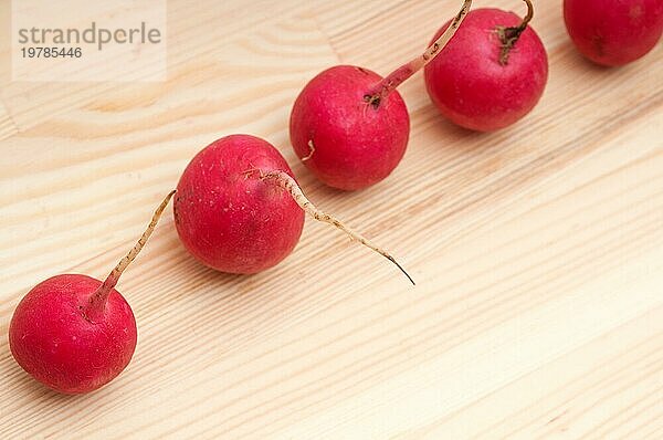 Frischer roter roher Rettich über Kiefernholztisch Großaufnahme