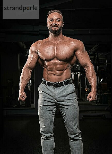 Attraktiver Mann in grauer Hose posiert im Fitnessstudio. Business und Bodybuilding Konzept. Sportliche Aktivitäten. Gemischte Medien