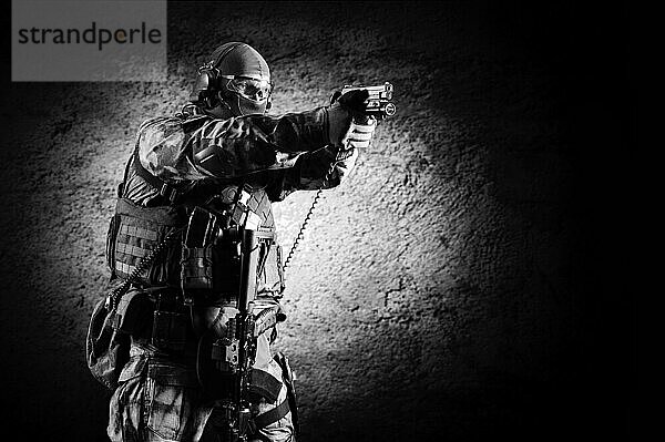 Ein Soldat einer Spezialeinheit steht mit einer Pistole in der Hand und zielt auf ein Ziel. Gemischte Medien