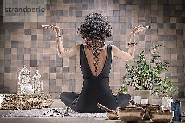 Bild einer erwachsenen Frau im Yogaraum. Meditation. Rückansicht. Das Konzept von Yoga und spirituellen Praktiken. Gemischte Medien