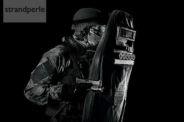 Ein mit einer Pistole bewaffneter Militärangehöriger in einer kugelsicheren Weste schützt sich mit einem Schild. Gemischte Medien