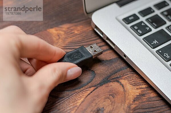 Bild eines an den Anschluss eines Laptops angeschlossenen USB Kabels. Das Konzept der modernen ultraschnellen Informationsübermittlung. Gemischte Medien