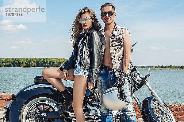 Verliebtes Paar reist auf einem Motorrad in der Nähe des Ozeans. Familie  Tourismus  Liebe Konzept. Gemischte Medien