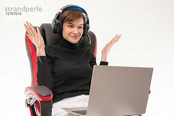 Porträt einer Frau  die in einem roten Gaming Stuhl sitzt und Kopfhörer trägt. Sie führt ein Vlog über ihre Webcam. Konzept des Online Lernens. Gemischte Medien