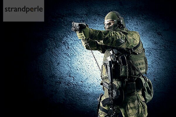 Ein Soldat einer Spezialeinheit steht mit einer Pistole in der Hand und zielt auf ein Ziel. Gemischte Medien