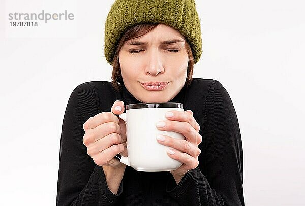 Porträt einer Frau mit grüner Strickmütze und einem Becher in der Hand. Konzept einer saisonalen Viruserkrankung. Gemischte Medien