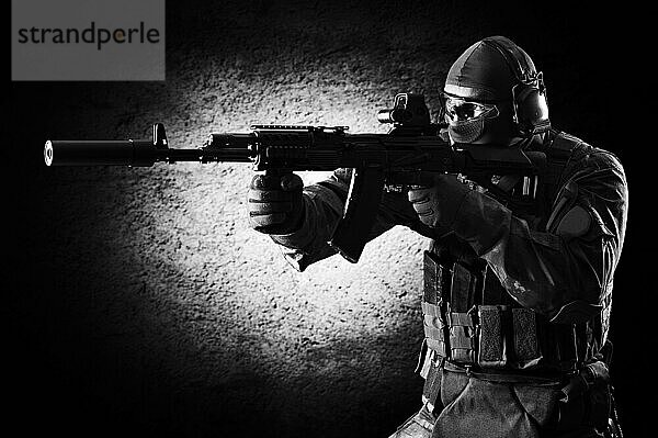 Ein Soldat einer Spezialeinheit steht mit einem Gewehr in der Hand und zielt auf ein Ziel. Gemischte Medien