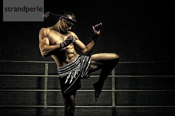 Kickboxer im Ring  umgeben von Scheinwerfern  dehnt sich vor dem Kampf. Macht Schwungbewegungen mit seinem Knie. Mongkhon. Gemischte Medien