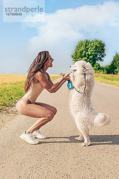 Porträt einer schönen sexy Frau in einem Bodysuit  die mit einem Hund spazieren geht. Liebe  Familie und Freundschaft Konzept. Gemischte Medien