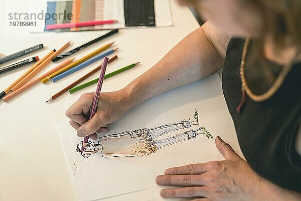 Modedesigner  der eine Modeskizze mit bunten Bleistiften zeichnet