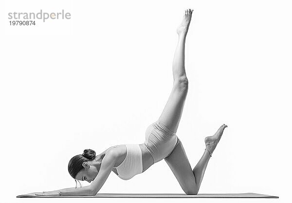 Sportliche junge Frau bei der Yoga Praxis. vor einem weißen Hintergrund. Das Konzept eines gesunden Lebensstils und eines natürlichen Gleichgewichts zwischen körperlicher und geistiger Entwicklung. Pilates  Stretching