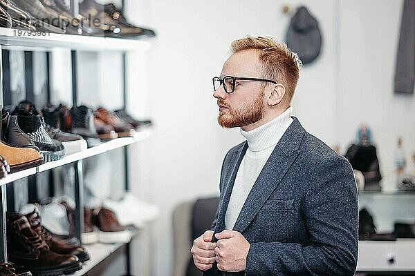 Ein erfolgreicher Geschäftsmann mit Brille wählt in einem Schuhgeschäft Schuhe für sich aus