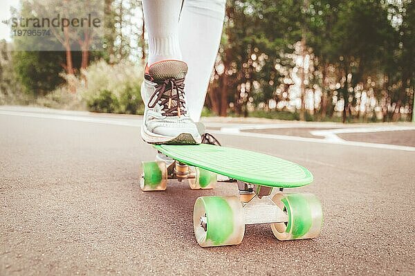Bilder eines Beines  das auf einem Skateboard steht. Sonniger Abend im Park. Skateboarding Konzept.