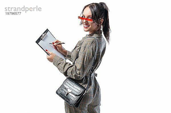 Charmantes Mädchen macht sich Notizen auf dem Tablet. Sie ist glücklich und lächelt. Business Stil. Konzept für ein Vorstellungsgespräch.