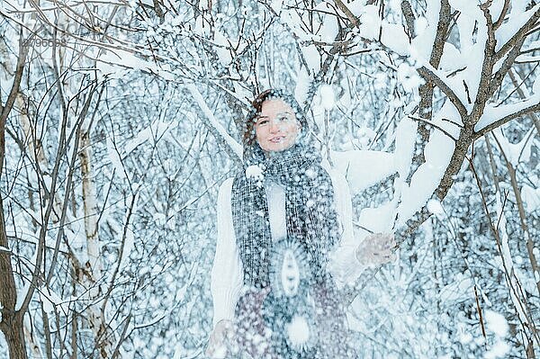 Das Mädchen hat Spaß im Winterwald. Sie bestreut alles rundherum mit Schnee. Winterurlaub Konzept. Tourismus.