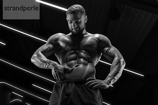 Porträt eines athletischen  muskulösen Mannes  der den Zustand der Bauchmuskeln überprüft. Fitness Konzept. Gemischte Medien