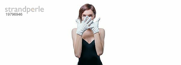 Verwirrtes Mädchen mit weißen Handschuhen posiert im Studio auf weißem Hintergrund. Porträt ohne Namen. Gemischte Medien