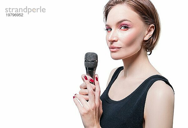 Porträt einer eleganten  stilvollen Frau mit einem Mikrofon. Weißer Hintergrund. Karaoke Konzept.