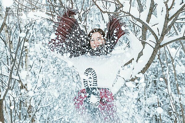 Das Mädchen hat Spaß im Winterwald. Sie bestreut alles rundherum mit Schnee. Winterurlaub Konzept. Tourismus.