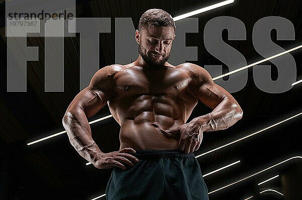 Porträt eines athletischen  muskulösen Mannes  der den Zustand der Bauchmuskeln überprüft. Fitnesskonzept