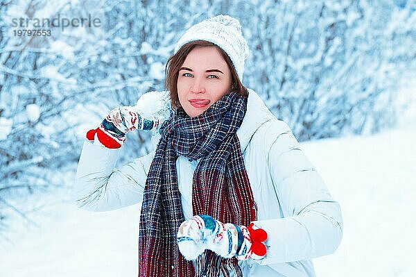Porträt eines schönen Mädchens  das einen Schneeball wirft. Konzept für Weihnachtsferien  Winterspiele  Glück und Spaß. Gemischte Medien