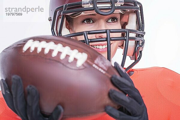 Porträt eines lächelnden Mädchens in der Uniform eines American Football Spielers. Weißer Hintergrund. Sportliches Konzept. Gemischte Medien