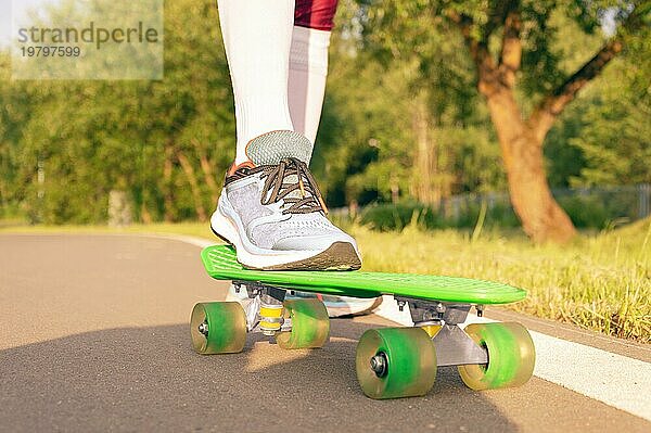 Bilder eines Beines  das auf einem Skateboard steht. Sonniger Abend im Park. Skateboarding Konzept.