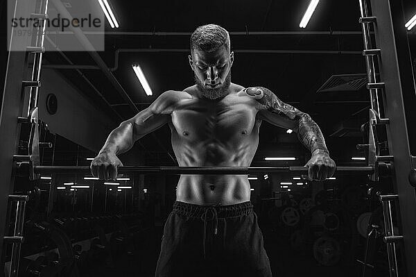 Porträt eines Sportlers  der vor einer Langhantel im Fitnessstudio steht. Bodybuilding und Fitness Konzept.
