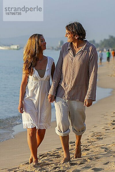 Junges Paar spaziert am Strand  Mann und Frau Hand in Hand