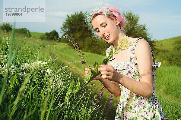 Porträt eines glücklichen jungen niedlichen Mädchen mit bunten Haaren sammelt Blumen neben einer Landstraße bei Sonnenuntergang. Das Konzept der menschlichen Harmonie mit der Natur des Frühlings und Glück