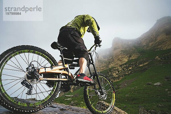 Extreme Mountainbike Sportler Mann mit Helm fahren im Freien vor einem Hintergrund von Felsen. Lebensstil. Trial