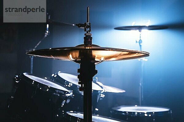 Nahaufnahme Schlagzeug in einem dunklen Raum vor dem Hintergrund des Scheinwerfers. Atmosphärisches Hintergrundsymbol für das Spielen von Rock oder Jazz Schlagzeug. Kupferplatten auf einem kalten Hintergrund