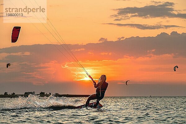 Junge Frau professionelle Kiter führt Fahrt schönen Hintergrund des Sonnenuntergangs und Meer