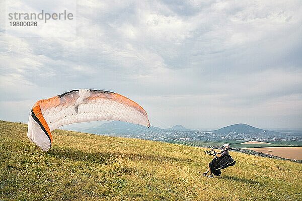 Der Gleitschirmflieger öffnet seinen Fallschirm  bevor er von einem Berg im Nordkaukasus abhebt. Füllen des Fallschirmflügels mit Luft vor dem Absprung