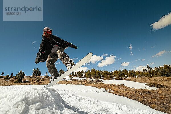 Eine Snowboarderin macht einen Sprungtrick und verdeckt dabei die Sonne. Flying Skifahrer vor dem Hintergrund der Himmel und Wolken