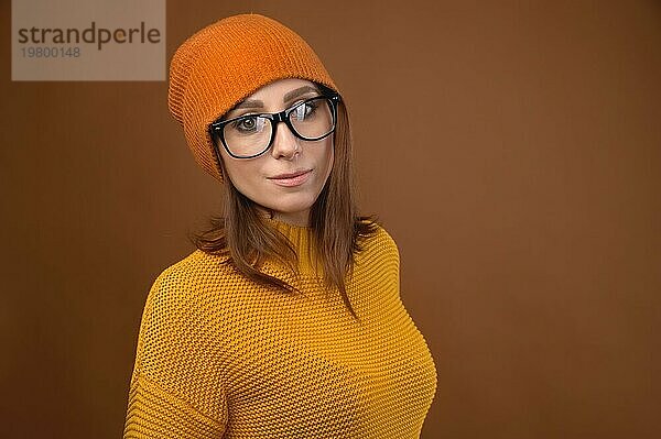 Attraktive kaukasische Frau mittleren Alters  die eine gelbe Strickmütze und eine Brille trägt  schaut in die Kamera. Sehproblem und Menschen mit Brille