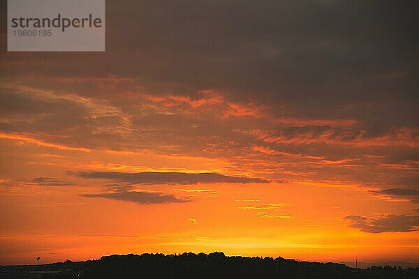 Abendhimmel nach Sonnenuntergang mit roten Wolken und die Silhouette des privaten Sektor einer kleinen Stadt