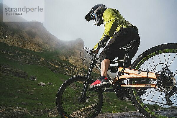 Extreme Mountainbike Sportler Mann mit Helm fahren im Freien vor einem Hintergrund von Felsen. Lebensstil. Trial