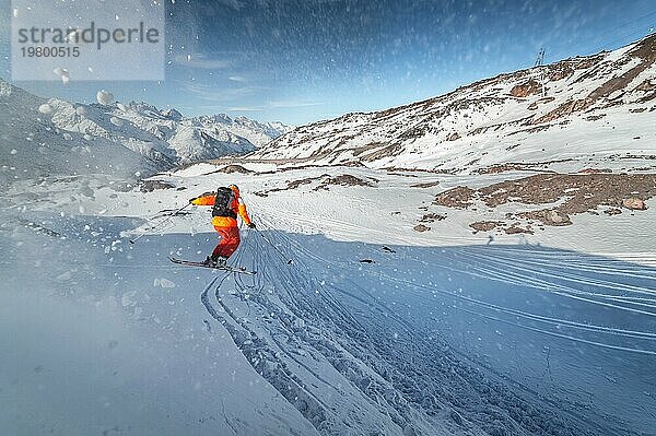 Ein Skifahrer fährt an einem sonnigen Tag bei Sonnenuntergang auf einer verschneiten Piste vor der Kulisse der Berge. Das Konzept des Skifahrens im Winter